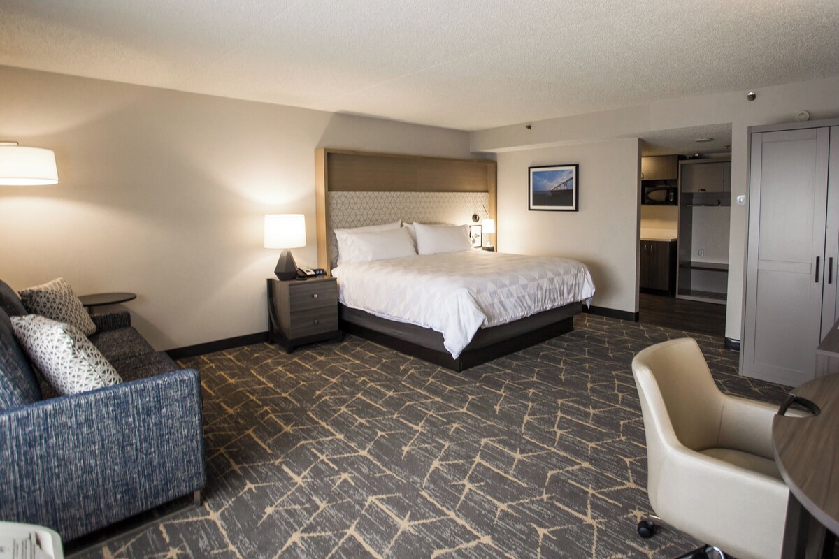 Ein Hotelzimmer mit Bett, Schreibtisch, Stuhl, Sofa und Kleiderschrank.