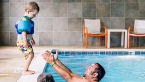 A swimming pool with tiled walls and a few chairs in the background.