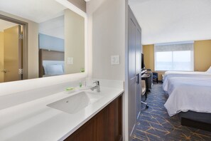 Ein Hotelzimmer mit Bad, einem Bett, einem Schreibtisch und einem großen Fenster.