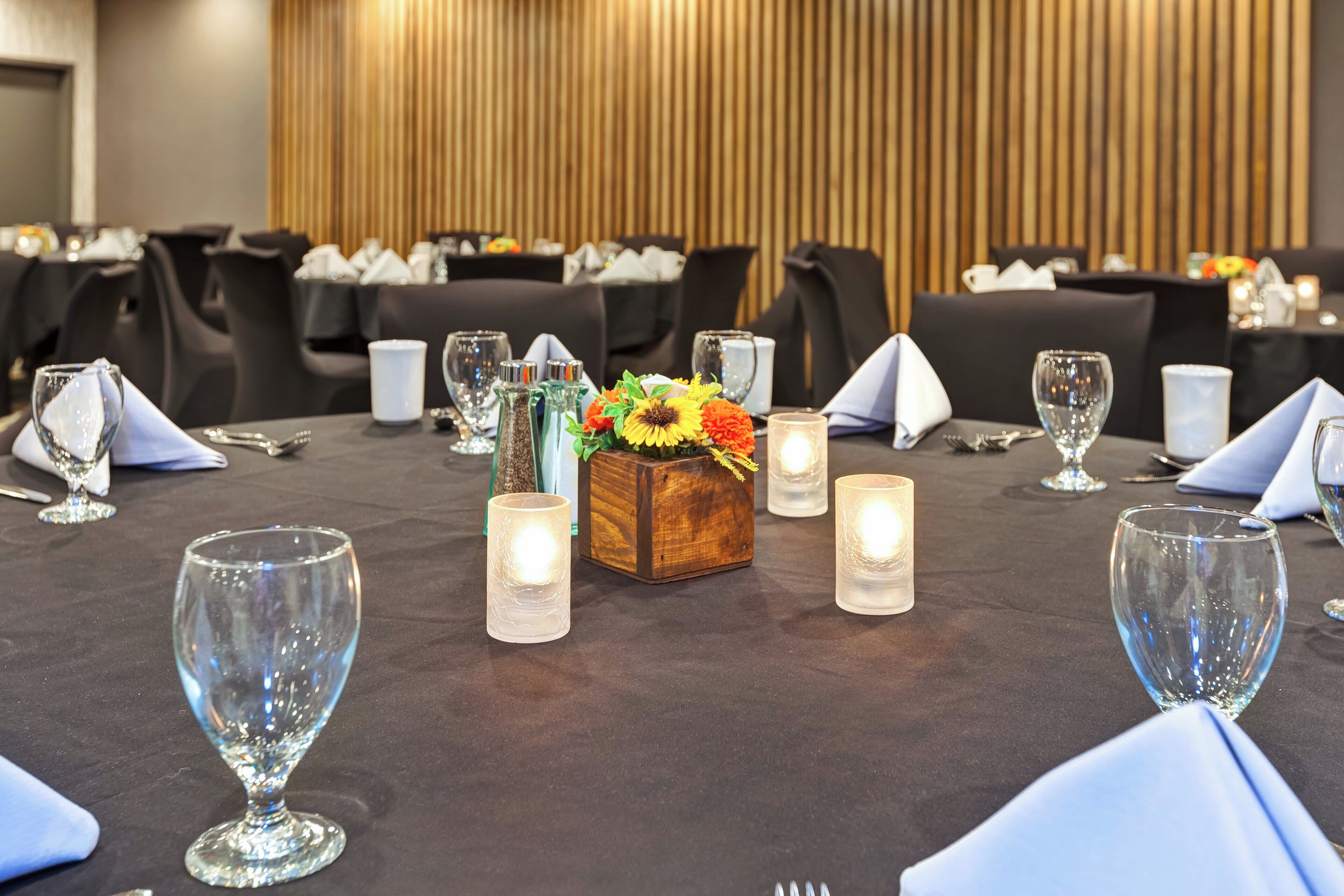 A table set for a formal event with glassware, napkins, and candles.