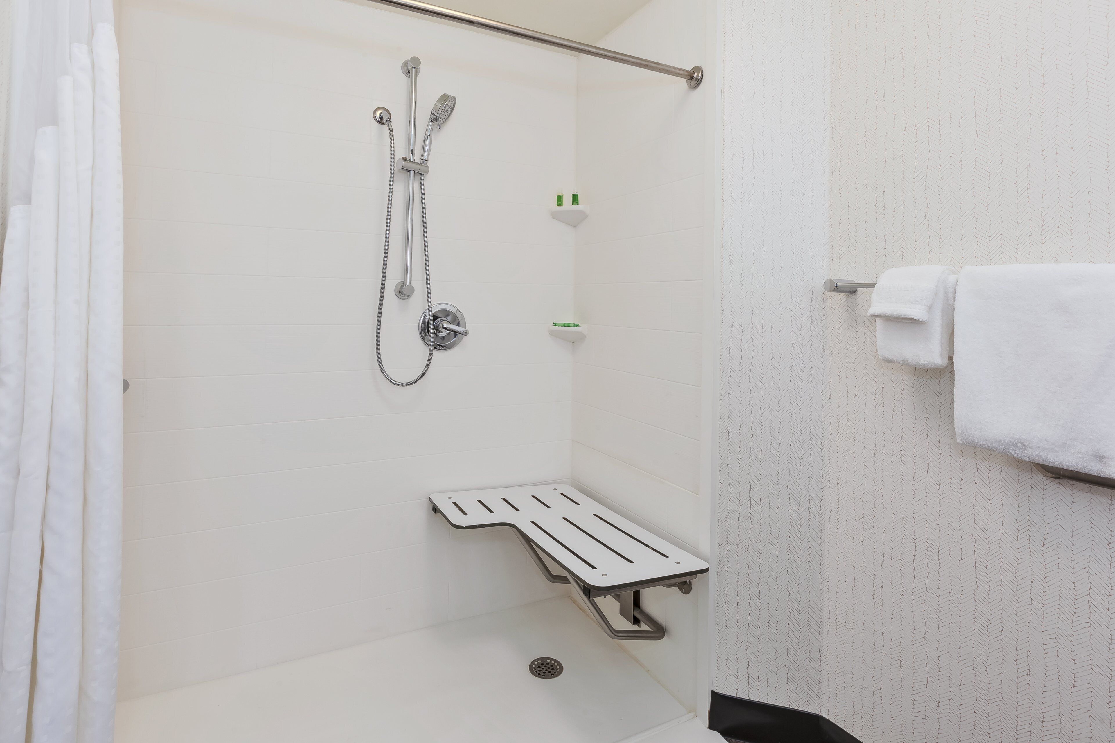 A shower area with a showerhead, a handheld showerhead, and a built-in shelf with toiletries.