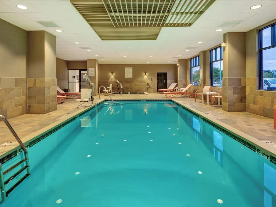A swimming pool with a tiled deck, lounge chairs, and a lifeguard chair.