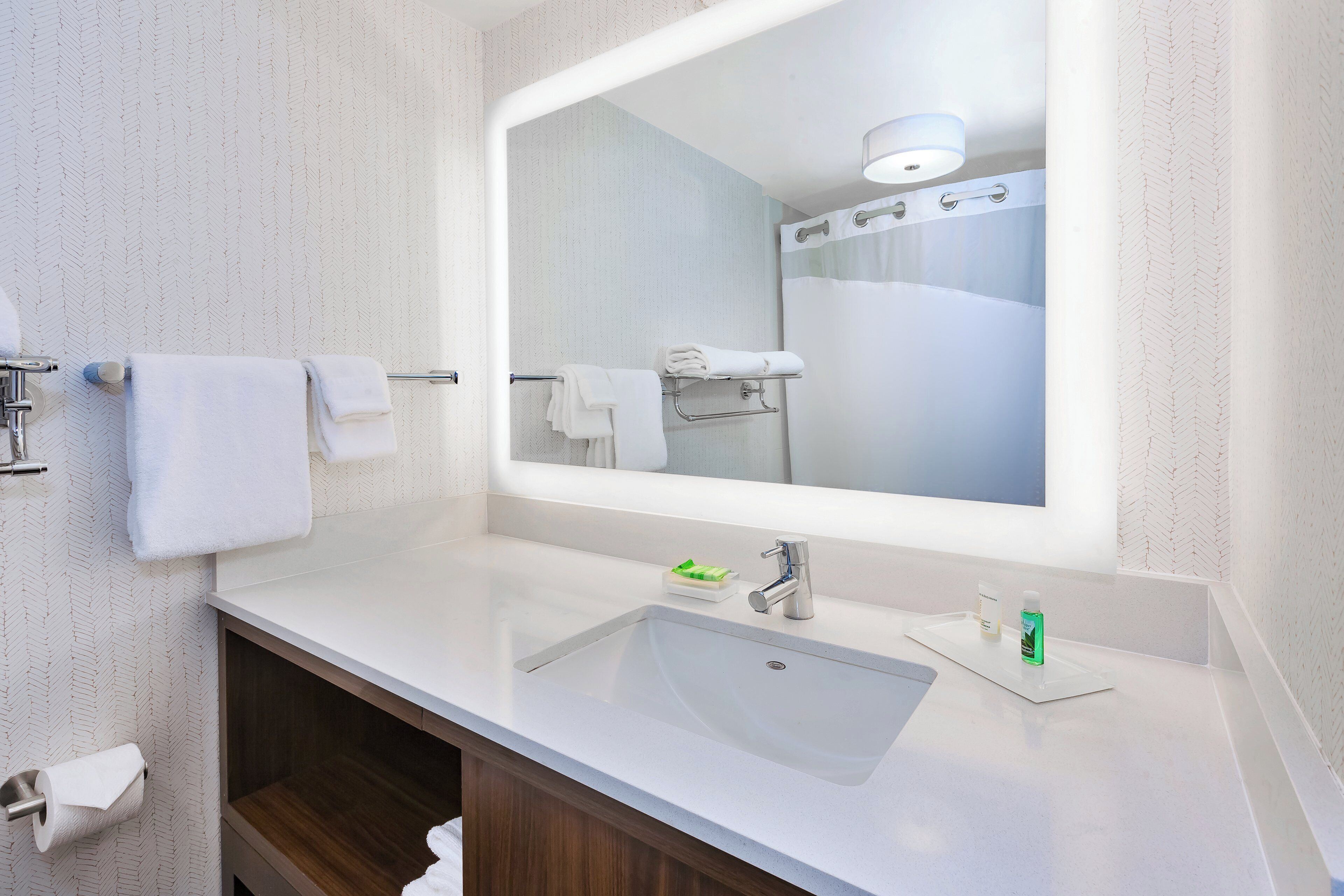 A modern bathroom with a large mirror, a sink, and a shower.