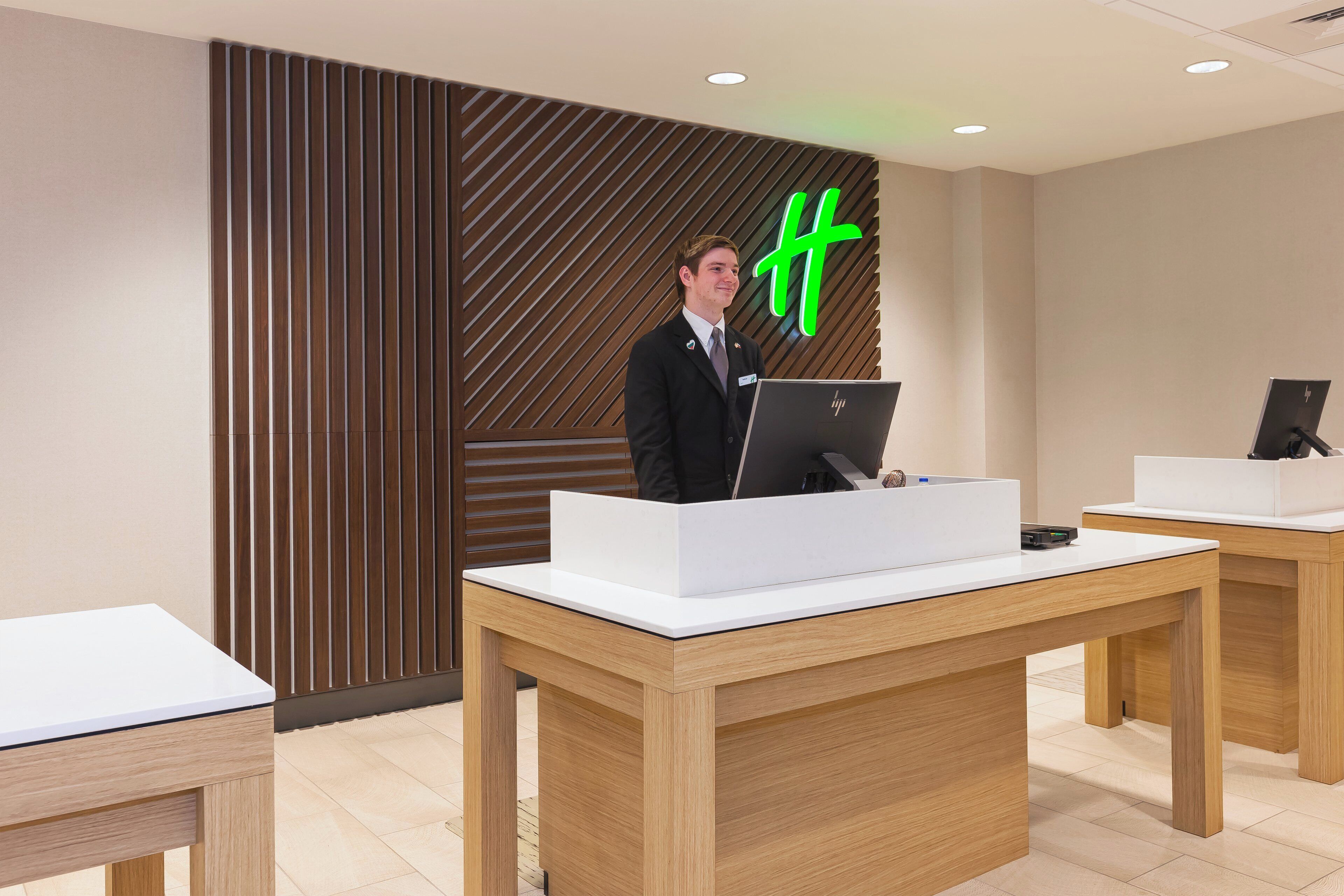 A hotel reception desk with a modern design, a nameplate, and a computer.
