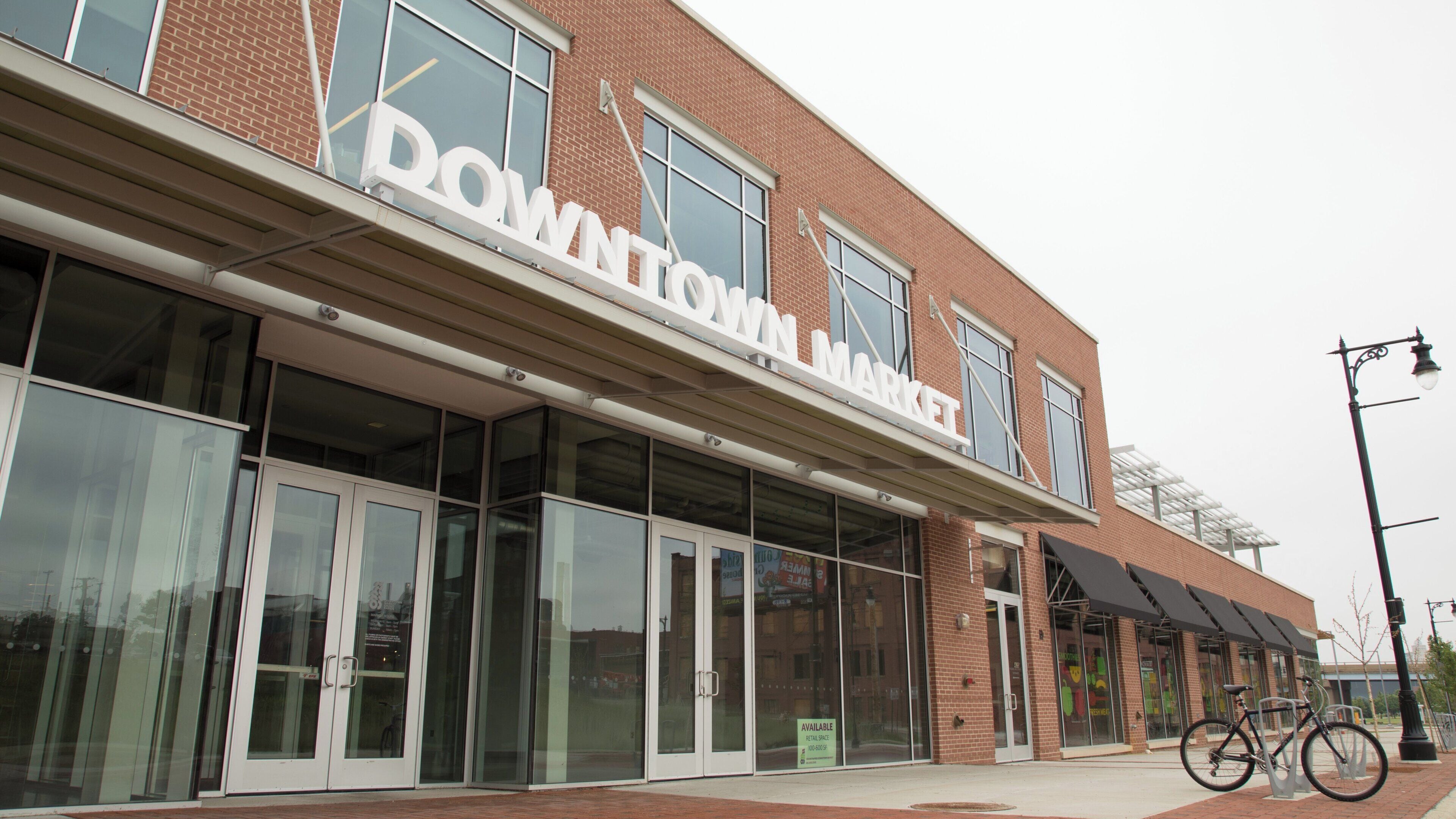 Un edificio de ladrillo con grandes escaparates de vidrio y un cartel que dice 'DOWNTOWN MARKET'.
