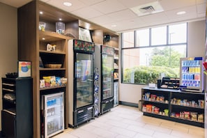 A self-service beverage station with refrigerated drink dispensers and snack vending machines. - Holiday Inn Grand Rapids Downtown by IHG (Grand Rapids)