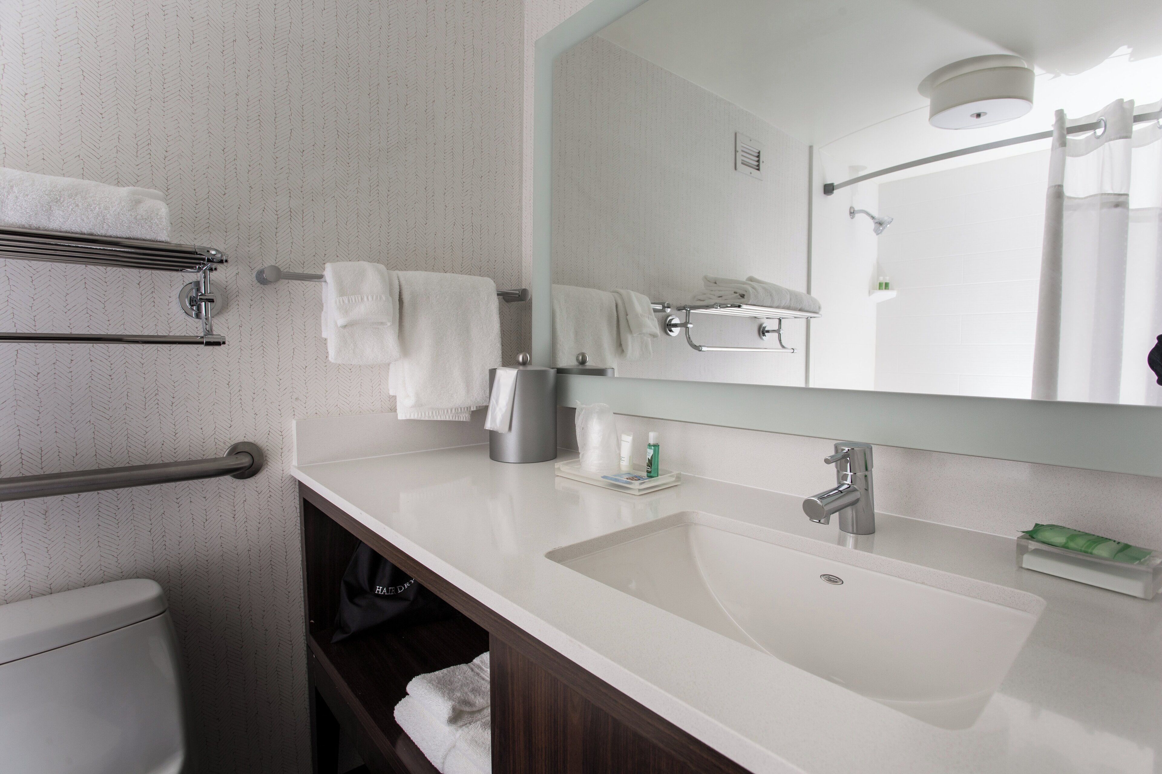Un baño moderno con lavamanos blanco, un espejo y un perchero para toallas.