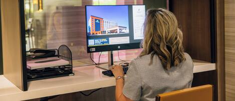 A hotel reception desk with a computer monitor displaying a building image, a keyboard, and a chair.