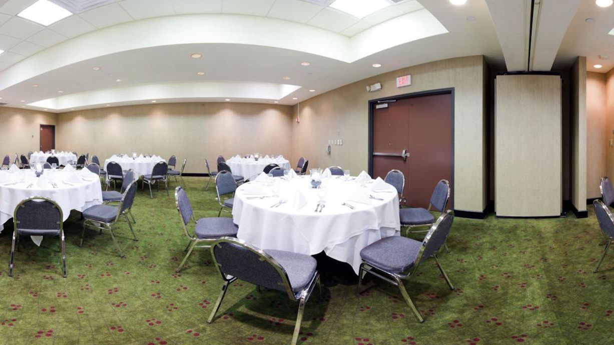 A conference room with round tables, chairs, and a carpeted floor.
