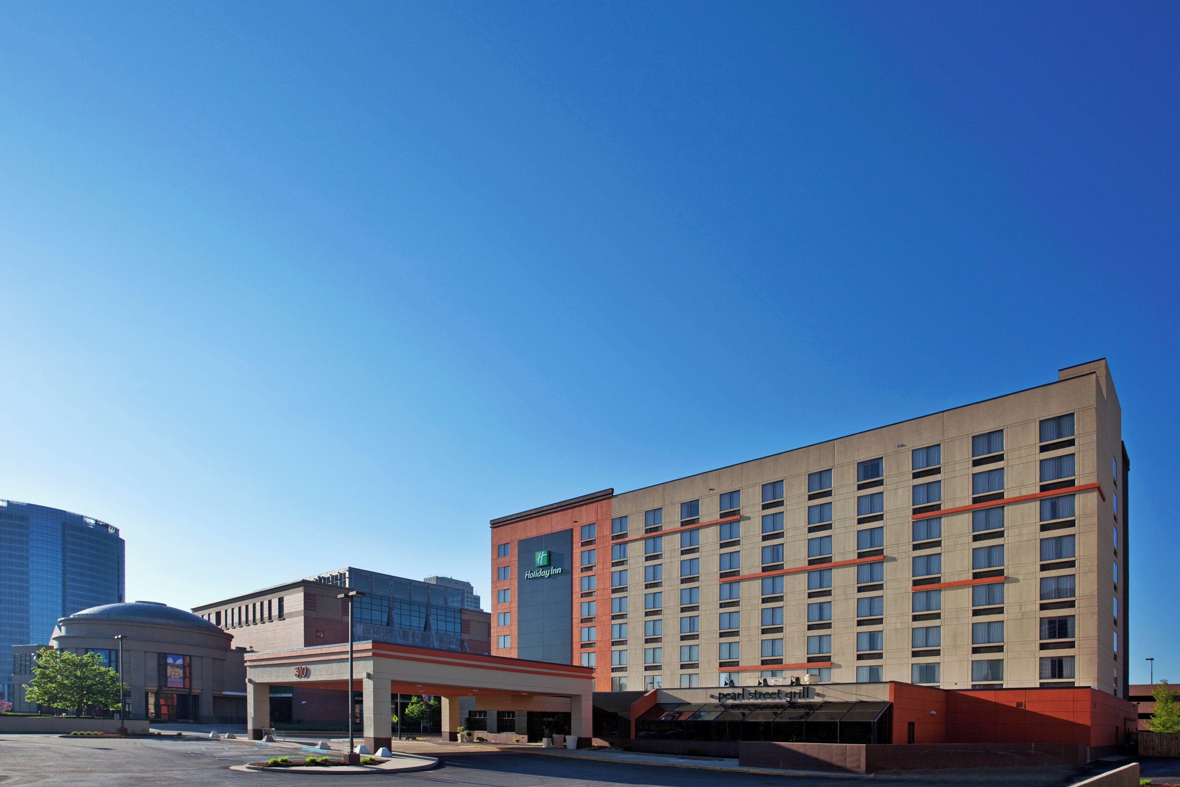 A multi-story hotel with a flat facade, a Holiday Inn sign, and a parking lot in front.