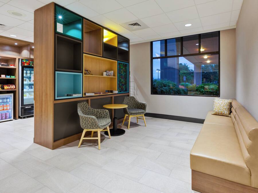 A modern lounge area with seating, a vending machine, and a large window.