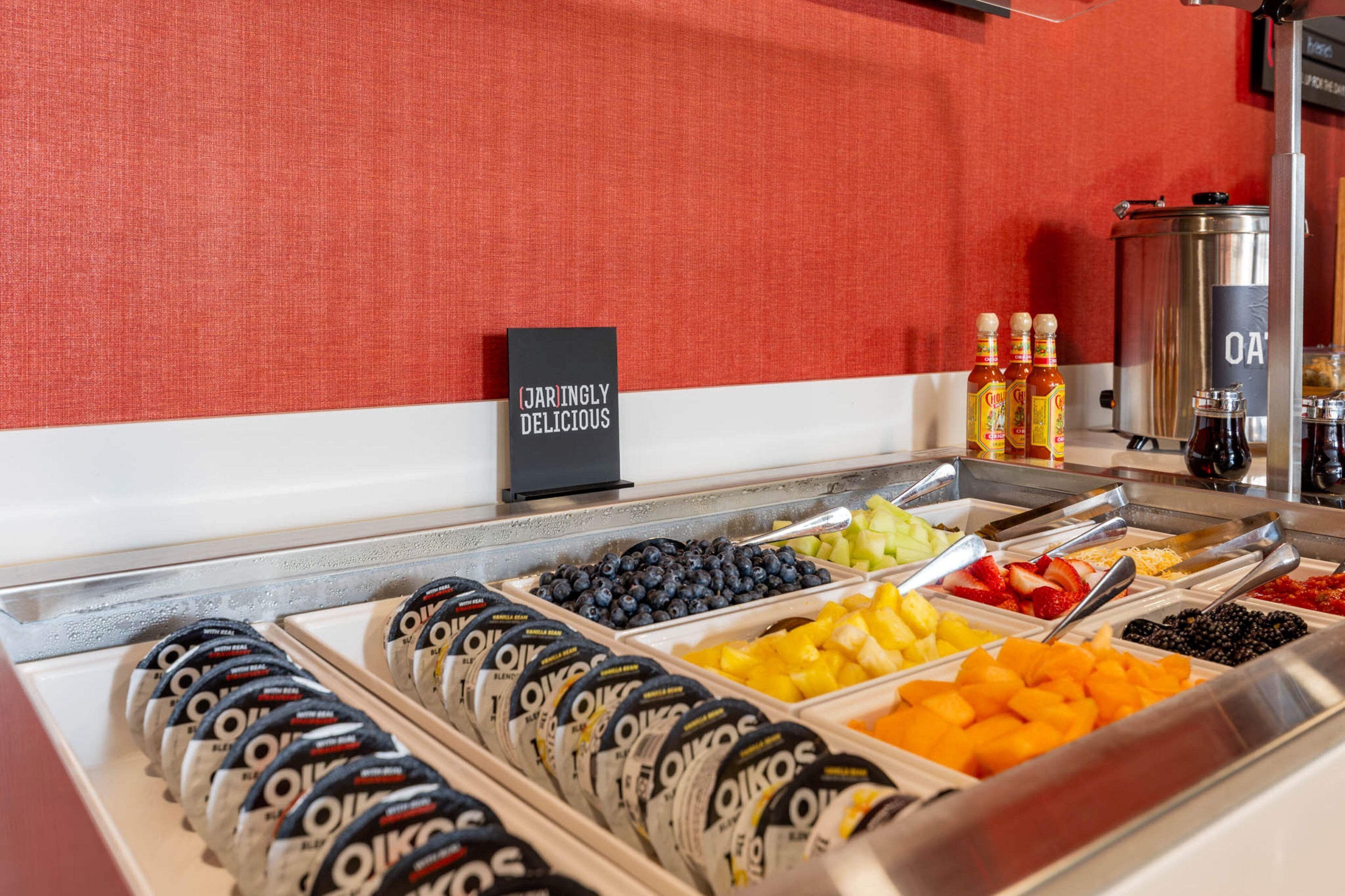 A buffet with various food options including fruits, yogurt, and condiments.