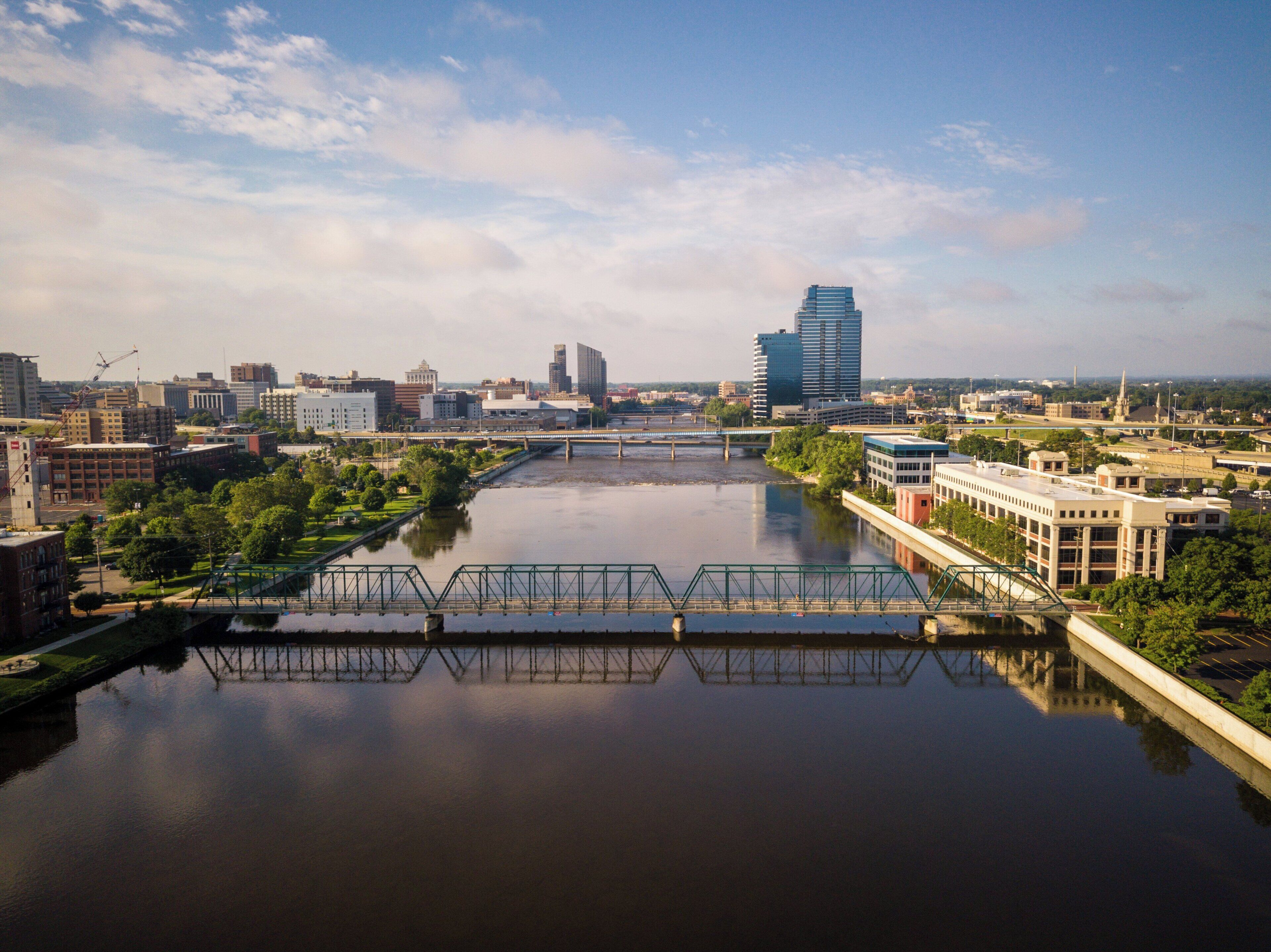 A river with a bridge, city buildings, and a clear sky.