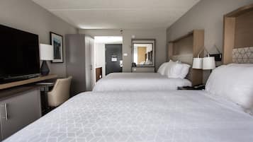 A hotel room with two beds, a desk with a TV, a chair, and a mirror.
