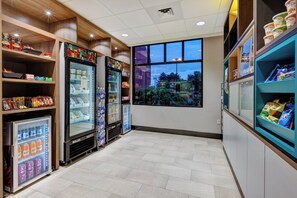 Un bar proposant des collations, doté de vitrines réfrigérées, d’étagères remplies de produits et d’une grande fenêtre donnant sur l’extérieur.