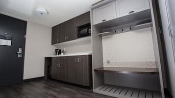 A modern kitchen with dark wood cabinets, a microwave, and a white tiled backsplash.