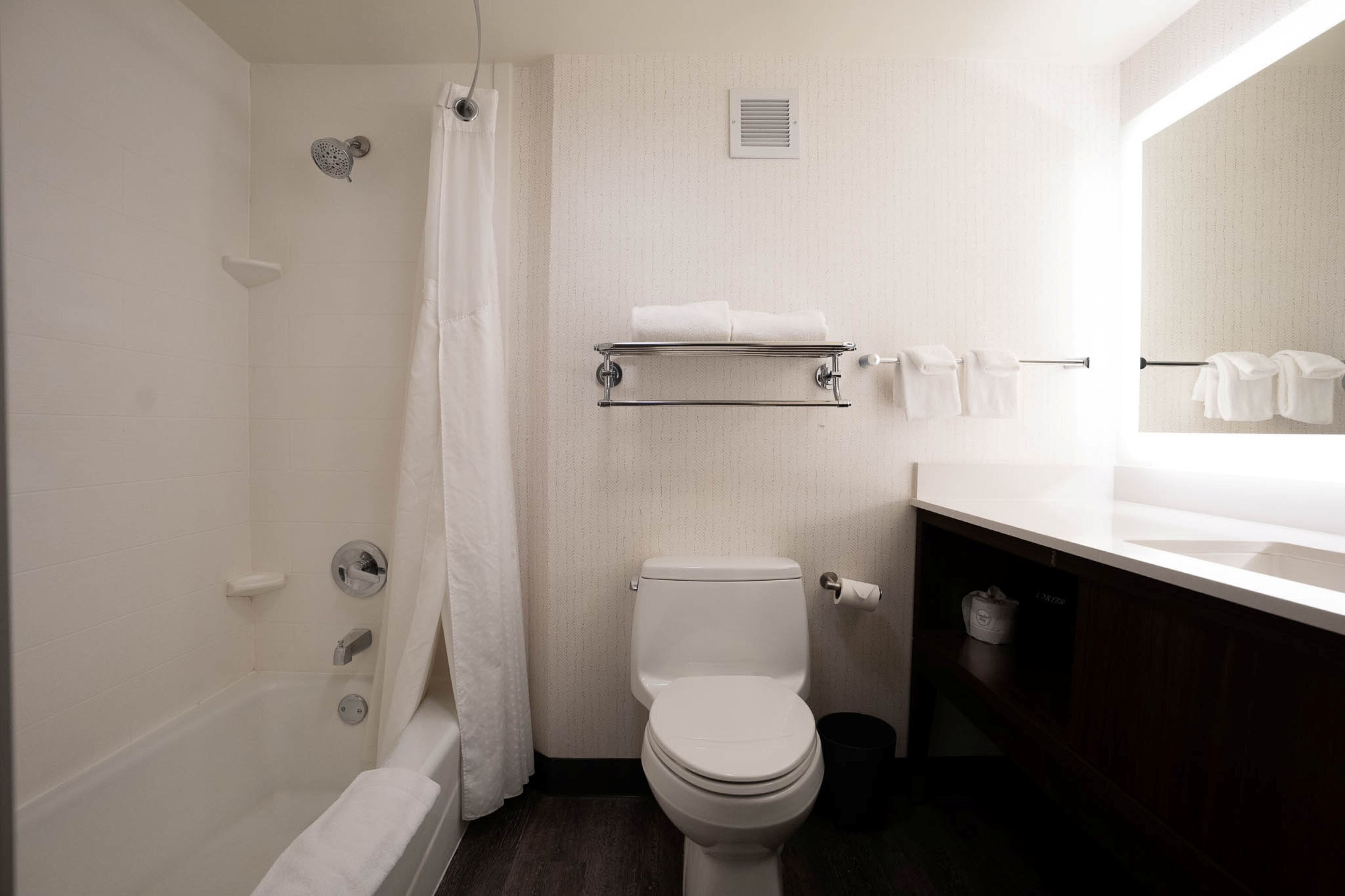 Een badkamer met een bad, toilet en een wastafel met spiegel.