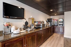 Una cocina equipada con una televisión de pantalla plana, cafeteras, una máquina para gofres y un refrigerador.