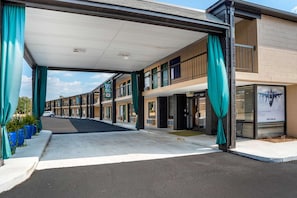 Un motel con área de estacionamiento techada, varias habitaciones y un anuncio visible de F16 Falcon.