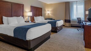A hotel room with two beds, a desk, a chair, and a television.