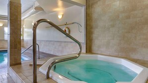 A spa area with a hot tub, a tiled wall, and a staircase.