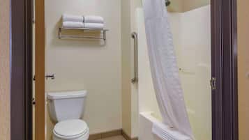A bathroom with a toilet, a towel rack with two towels, a shower with a curtain, and a grab bar.