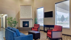 A modern lobby with a fireplace, comfortable seating, large windows, and a flat-screen TV.