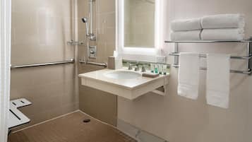 A modern bathroom with a shower, sink, and towel rack.