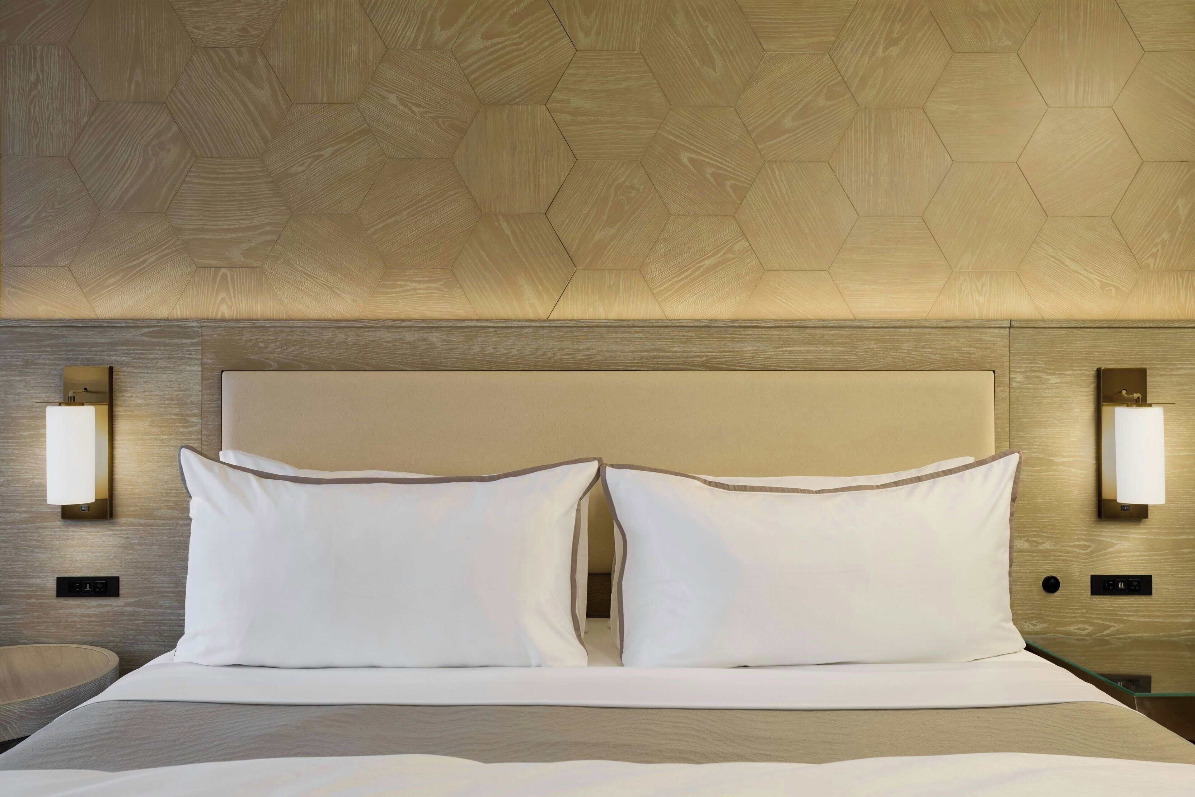 Een hotelkamer met een groot bed, twee bedlampen en een wand met een honingraatpatroon.