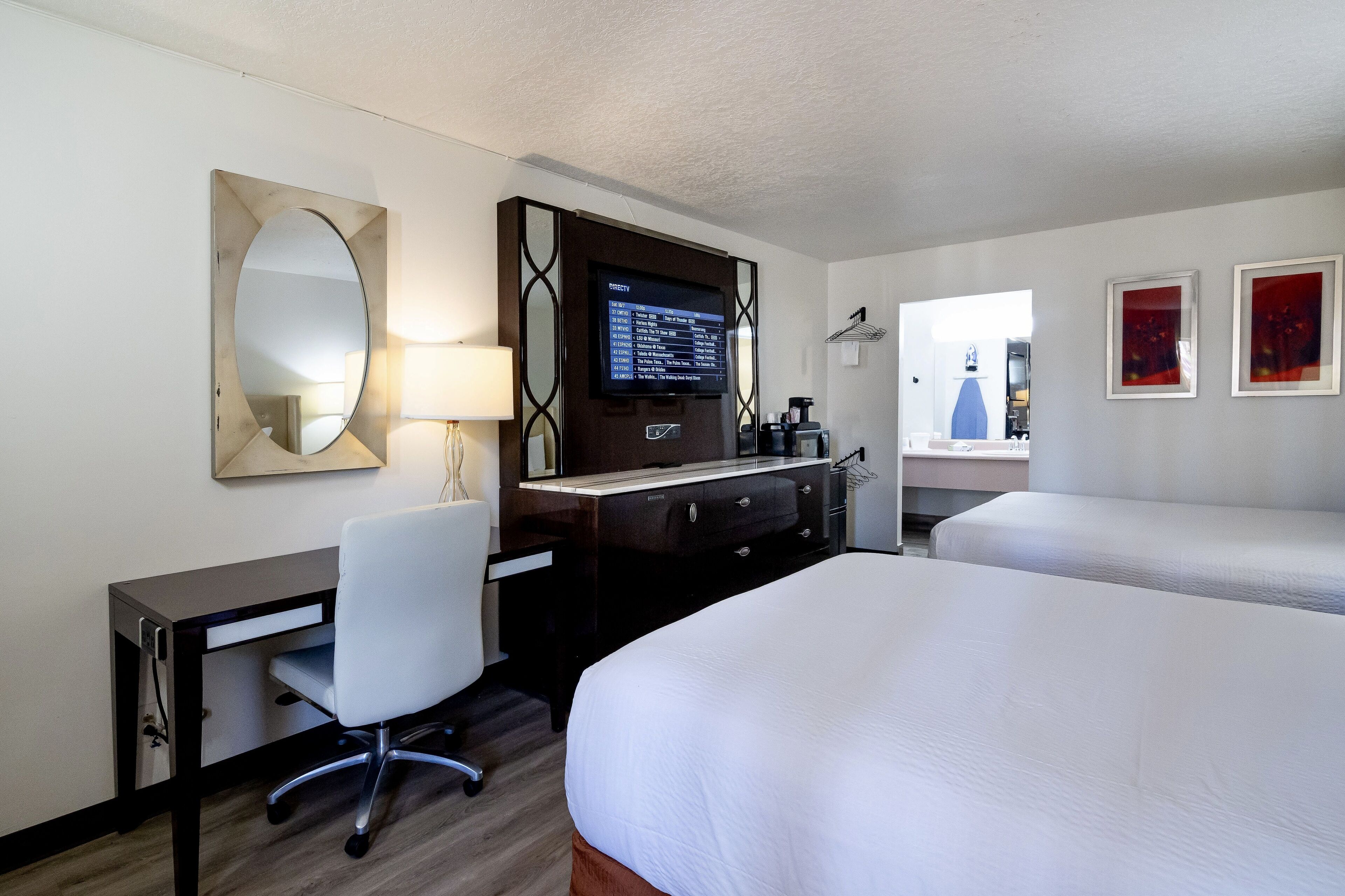 Ein Hotelzimmer mit Schreibtisch, Stuhl, Fernseher und zwei Betten.