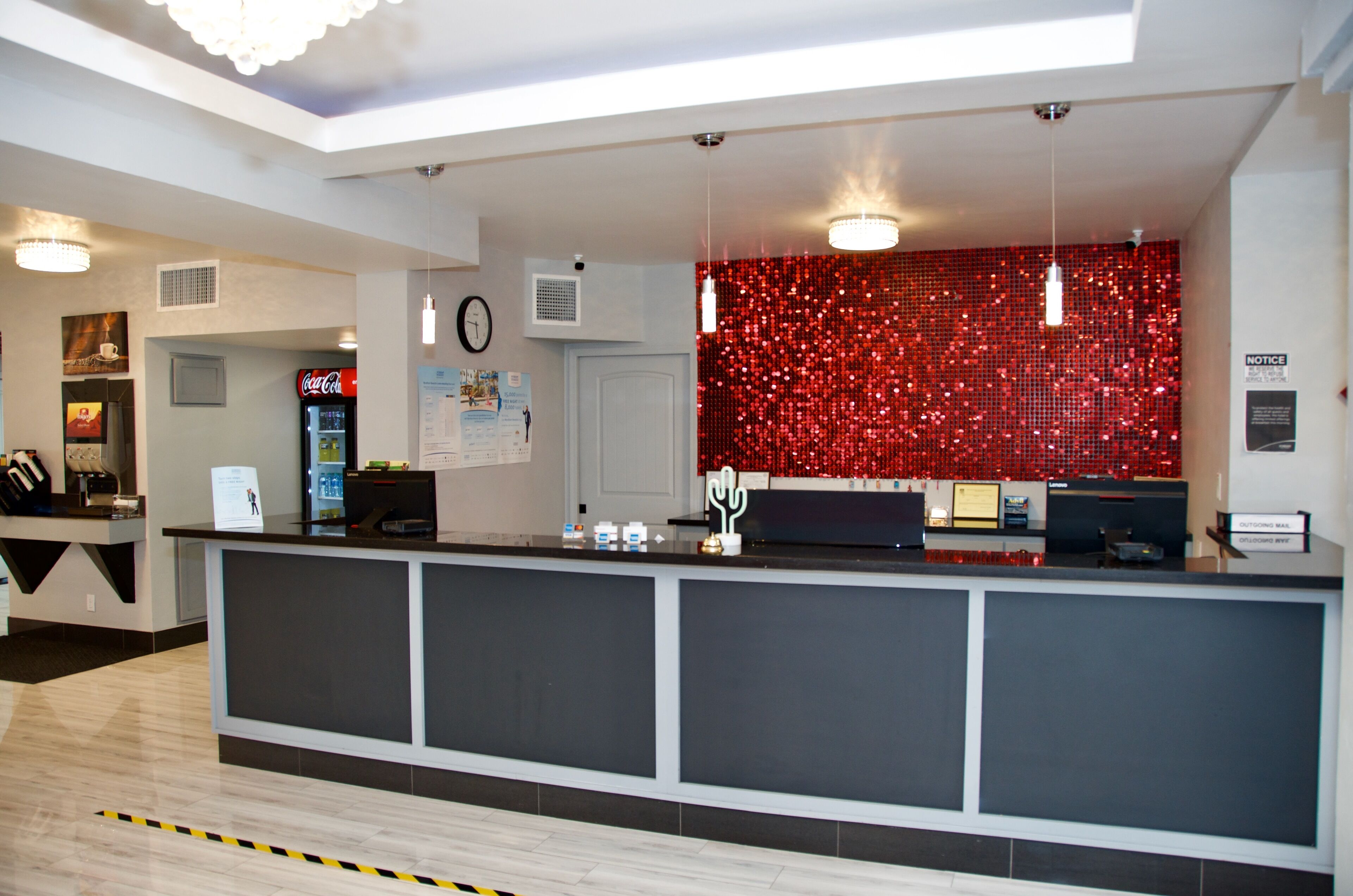 A reception area with a counter, a Coca-Cola refrigerator, a clock, and a red sequin wall.
