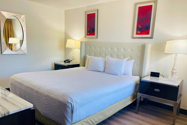 A hotel room with a large bed, two bedside tables, a mirror, and two abstract paintings on the wall. - Ramada by Wyndham Yuma (Yuma)