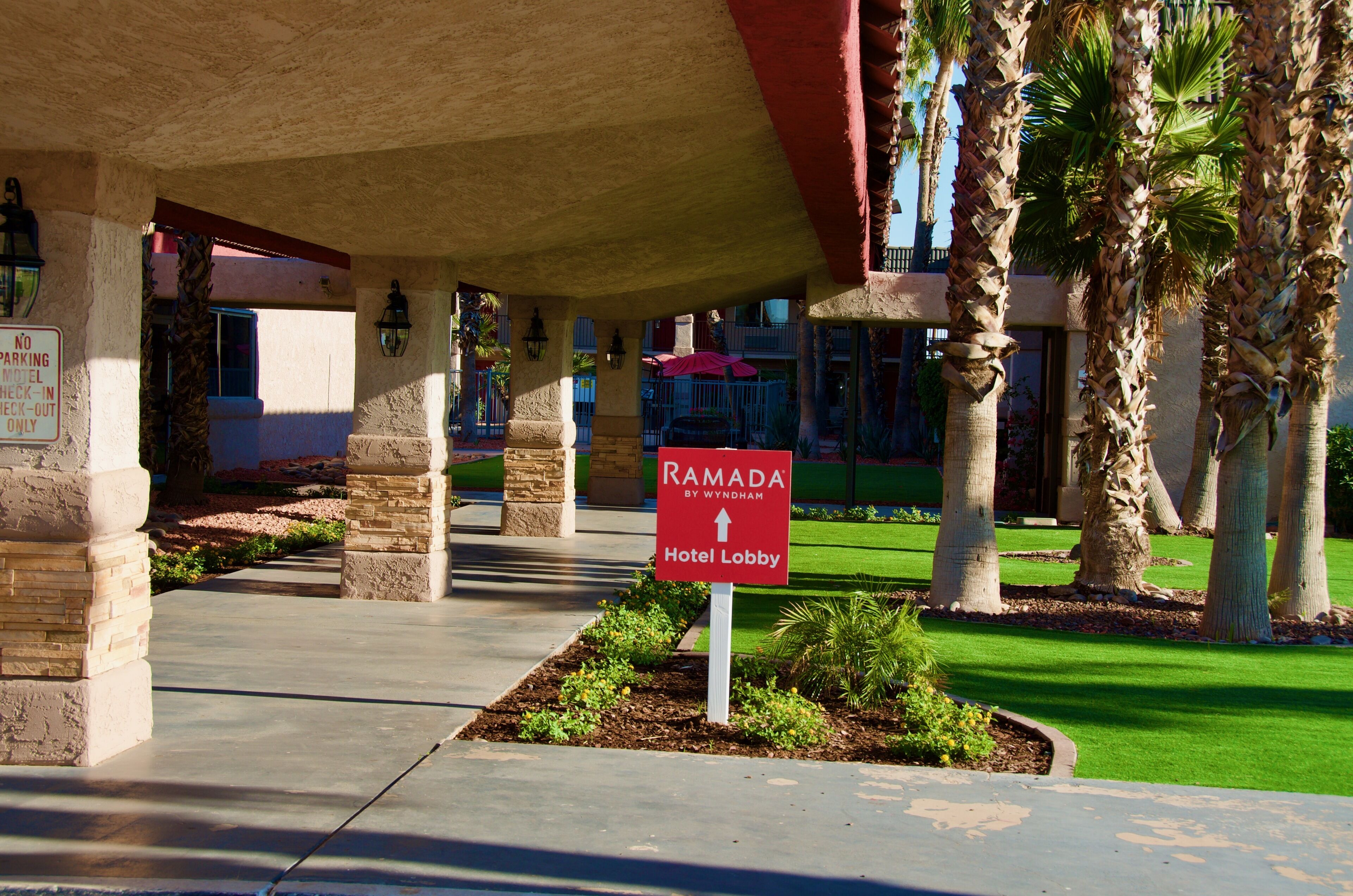 A hotel lobby with a sign indicating the direction to the Ramada Hotel Lobby.