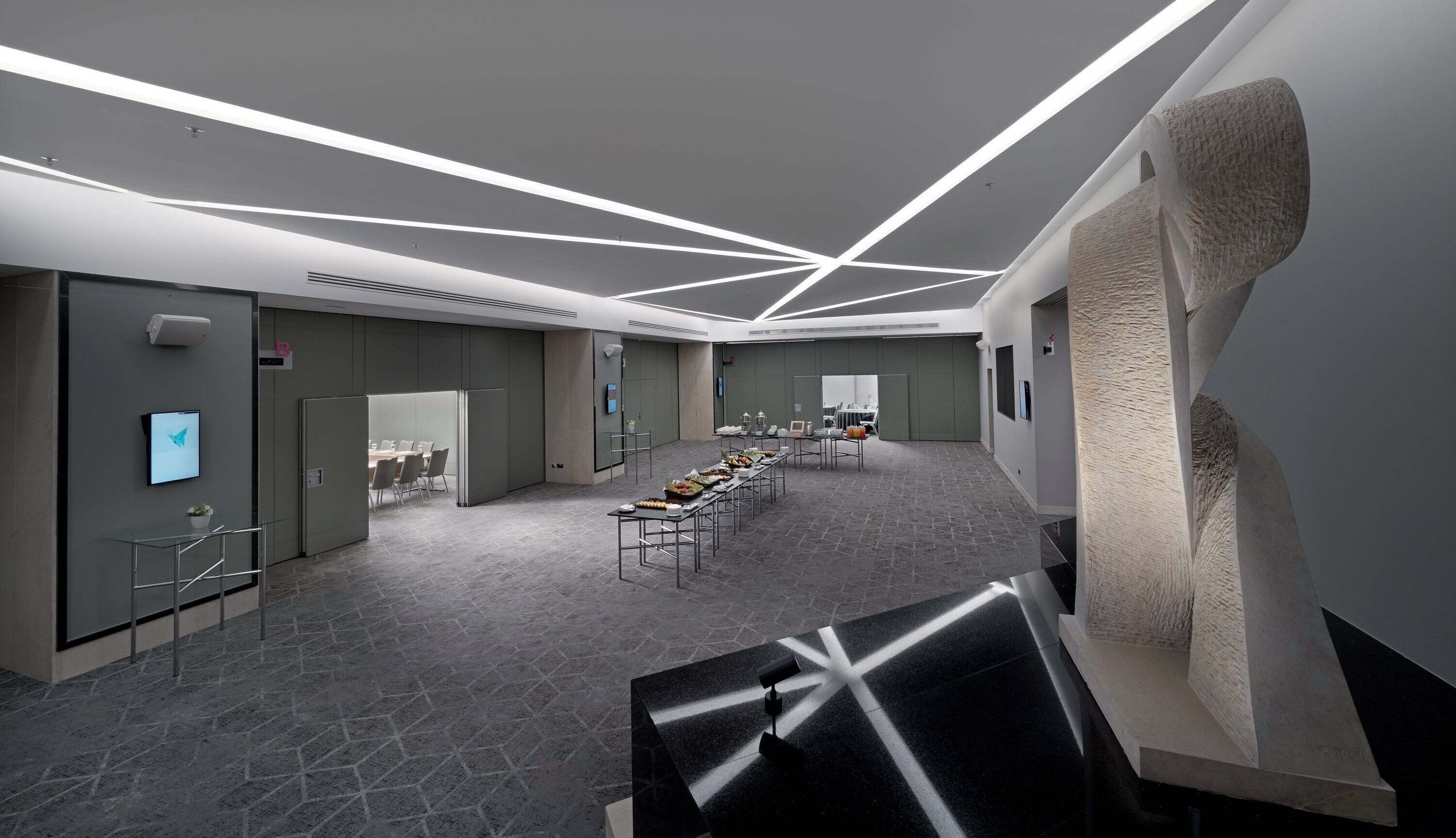 A modern conference room with a long table, chairs, and a projector screen.