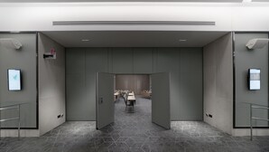 Un hall d’hôtel moderne avec un sol à motifs géométriques, un comptoir d’accueil et une salle de conférence en arrière-plan.