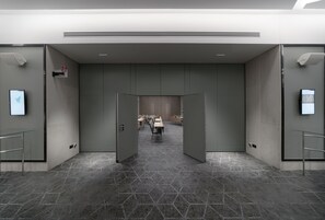 A modern hotel lobby with a geometric patterned floor, a reception desk, and a conference room in the background. - Crowne Plaza Athens City Centre by IHG (Athens)