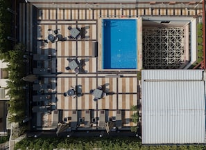 Vista aerea di una zona piscina sul tetto, con diverse poltrone prendisole e una piscina.