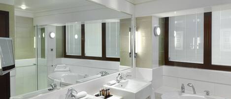 A modern bathroom with two sinks, a bathtub, and a large mirror.