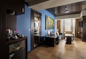 A modern hotel room with a living area, a kitchenette, and a large window with curtains. - Crowne Plaza Athens City Centre by IHG (Athens)