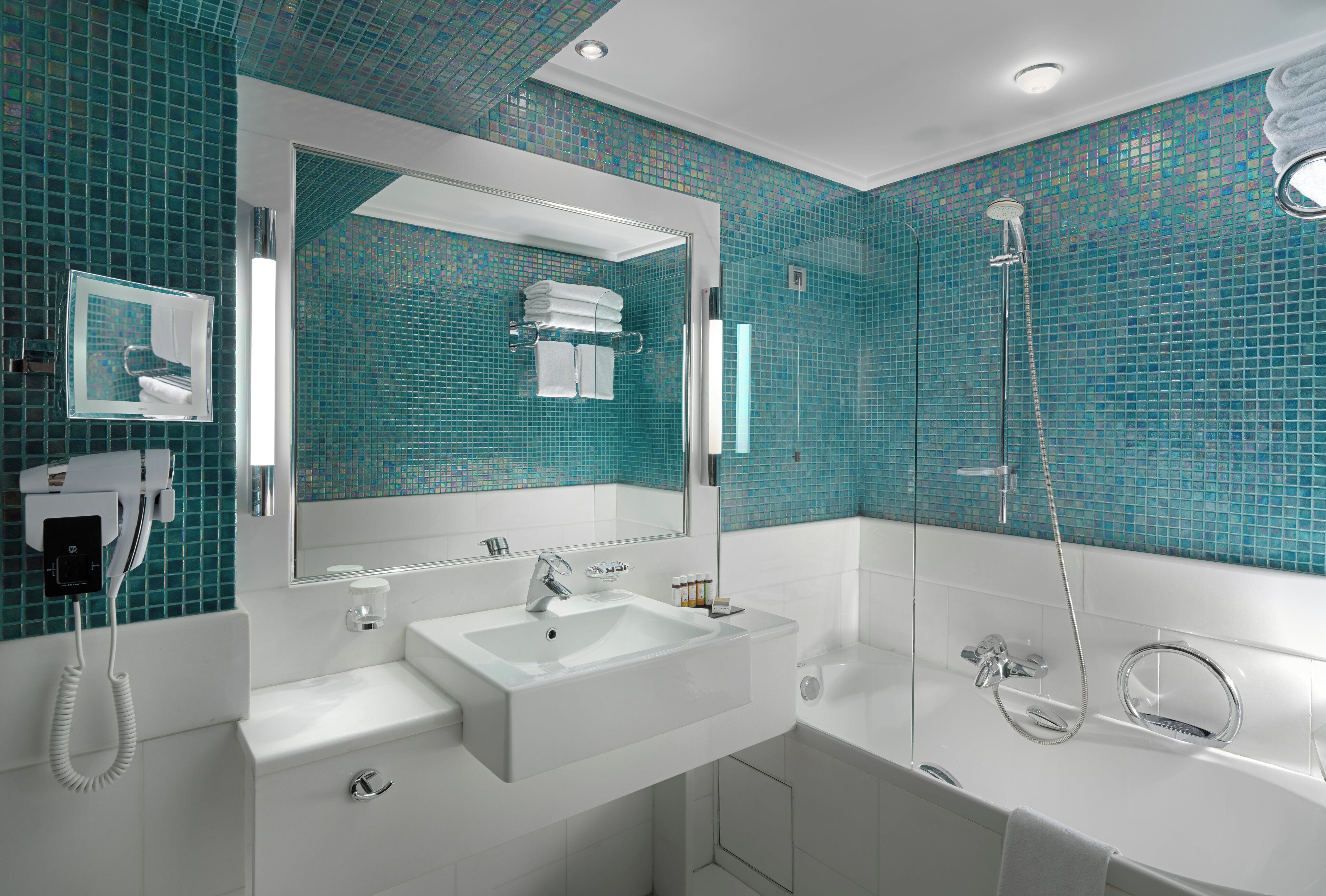 A modern bathroom with a large mirror, a sink, a shower, and a towel rack.