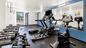 A gym with treadmills, an elliptical, and dumbbells.
