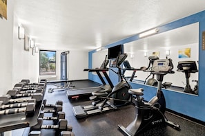 A gym with treadmills, an elliptical, and dumbbells.