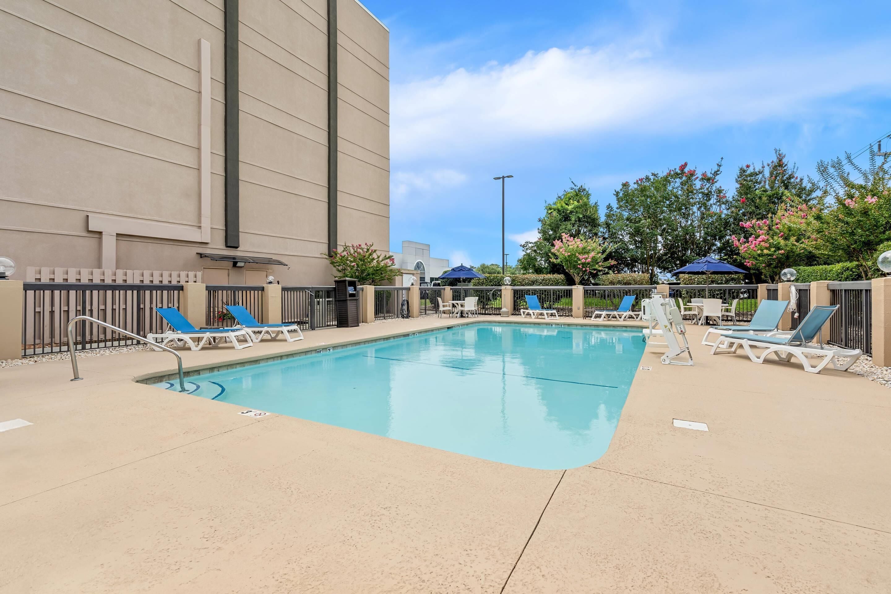 A swimming pool with lounge chairs and a building in the background.