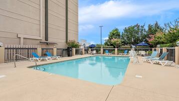 A swimming pool with lounge chairs and a building in the background.
