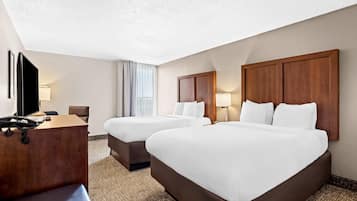 Une chambre d’hôtel avec deux lits, un bureau, un téléphone et une télévision.