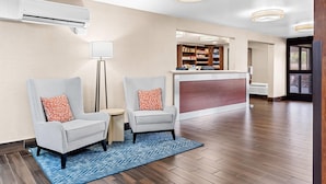 A hotel lobby with two armchairs, a reception desk, and a mirror reflecting the interior.