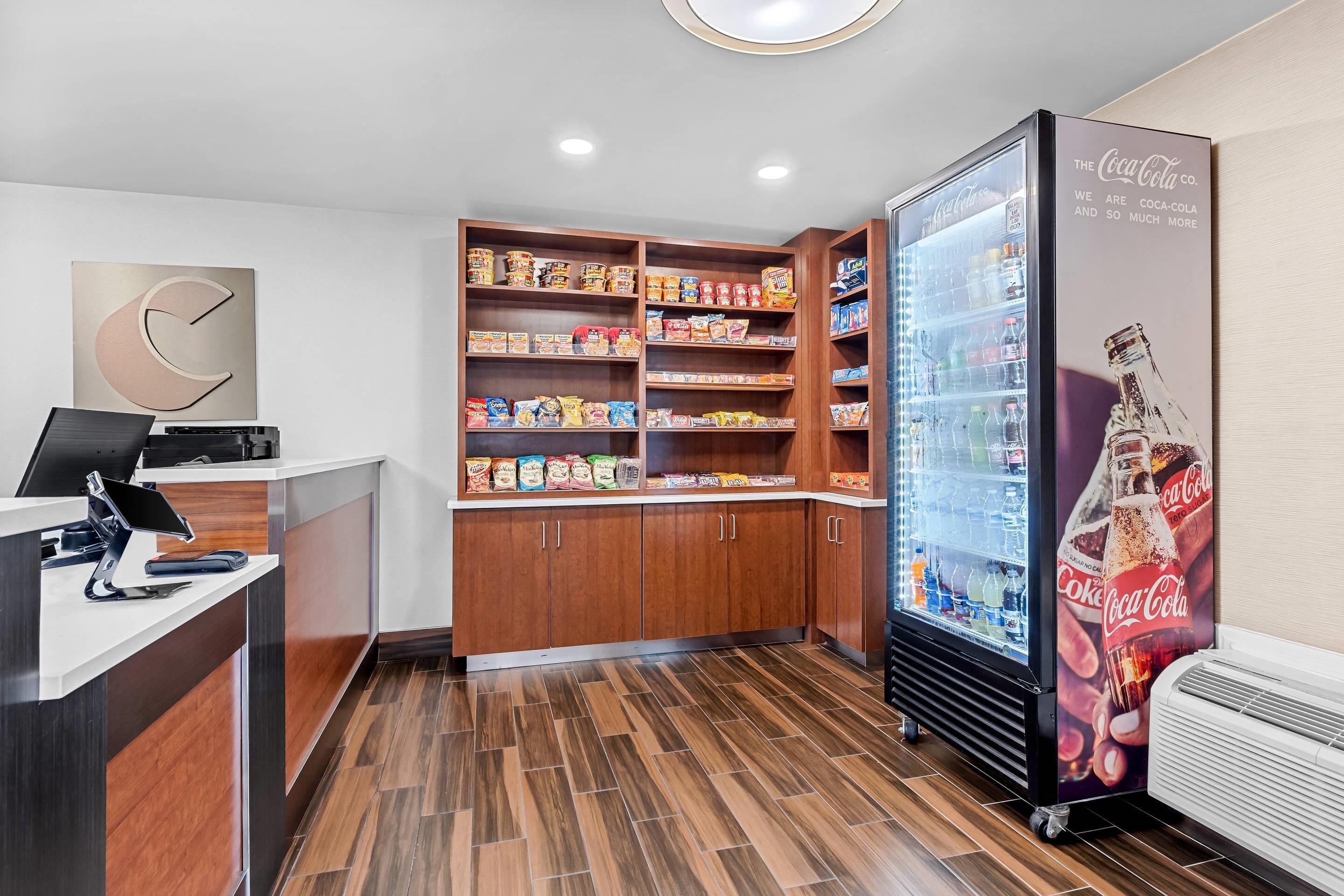 Una moderna zona de recepción con un mostrador de madera, un refrigerador de Coca-Cola y un estante para aperitivos.