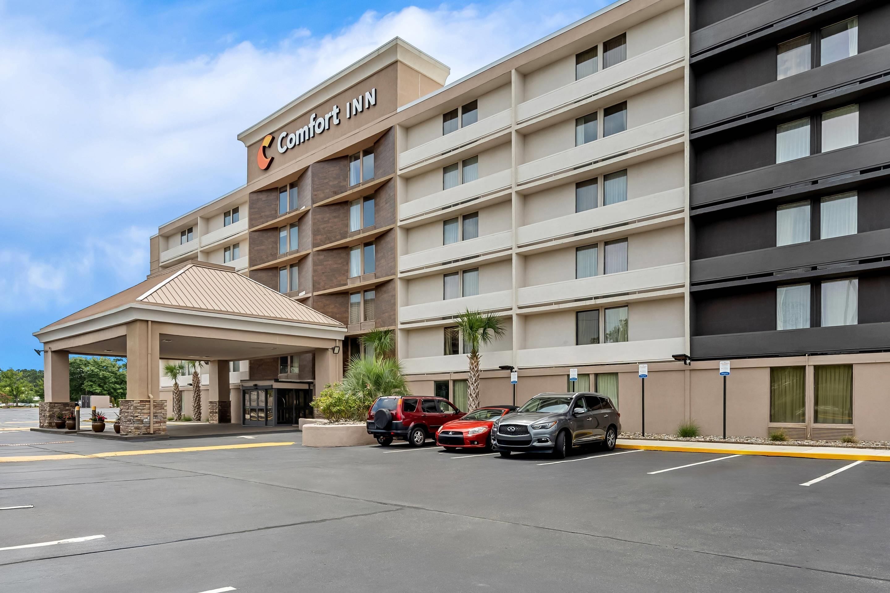 Un hotel Comfort Inn con entrada cubierta, varios pisos y un estacionamiento con varios automóviles.