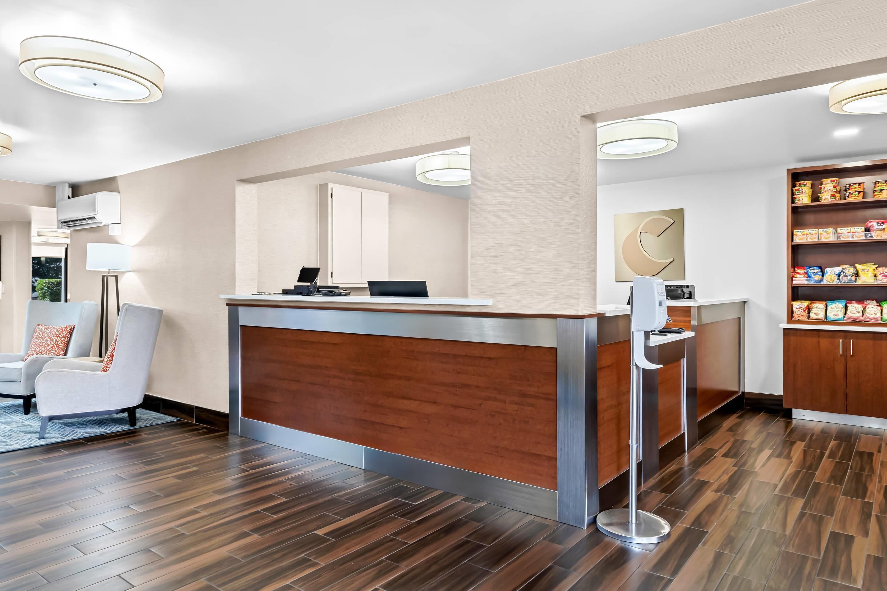 A reception area with a wooden reception desk, a white wall with a clock, and a shelf with snacks.
