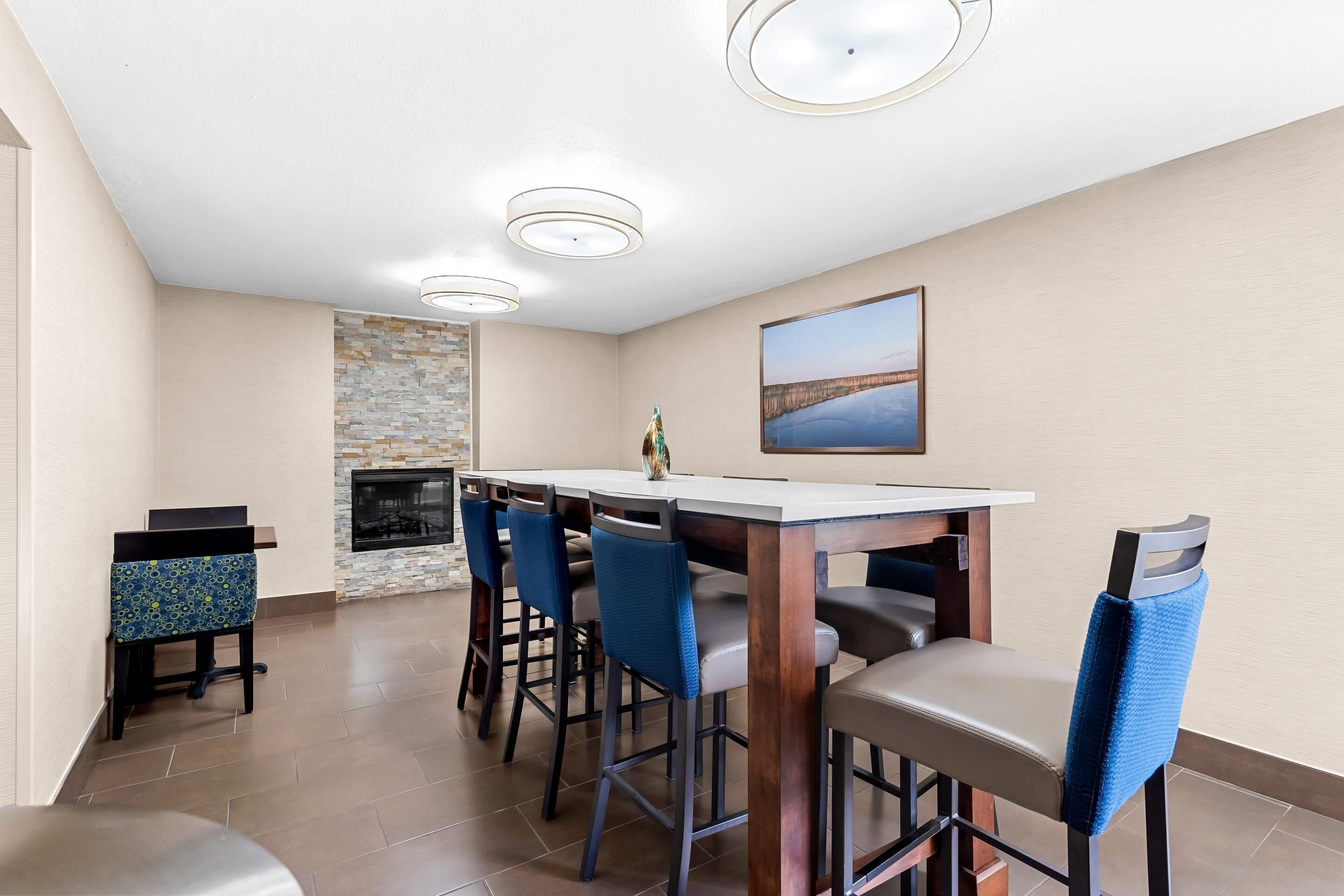 A dining area with a stone fireplace, a painting on the wall, and a modern ceiling light fixture.